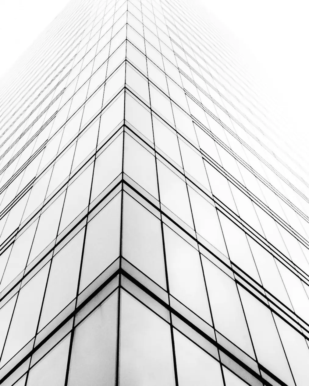 Torre de vidro vista de baixo para cima, convergindo para o céu