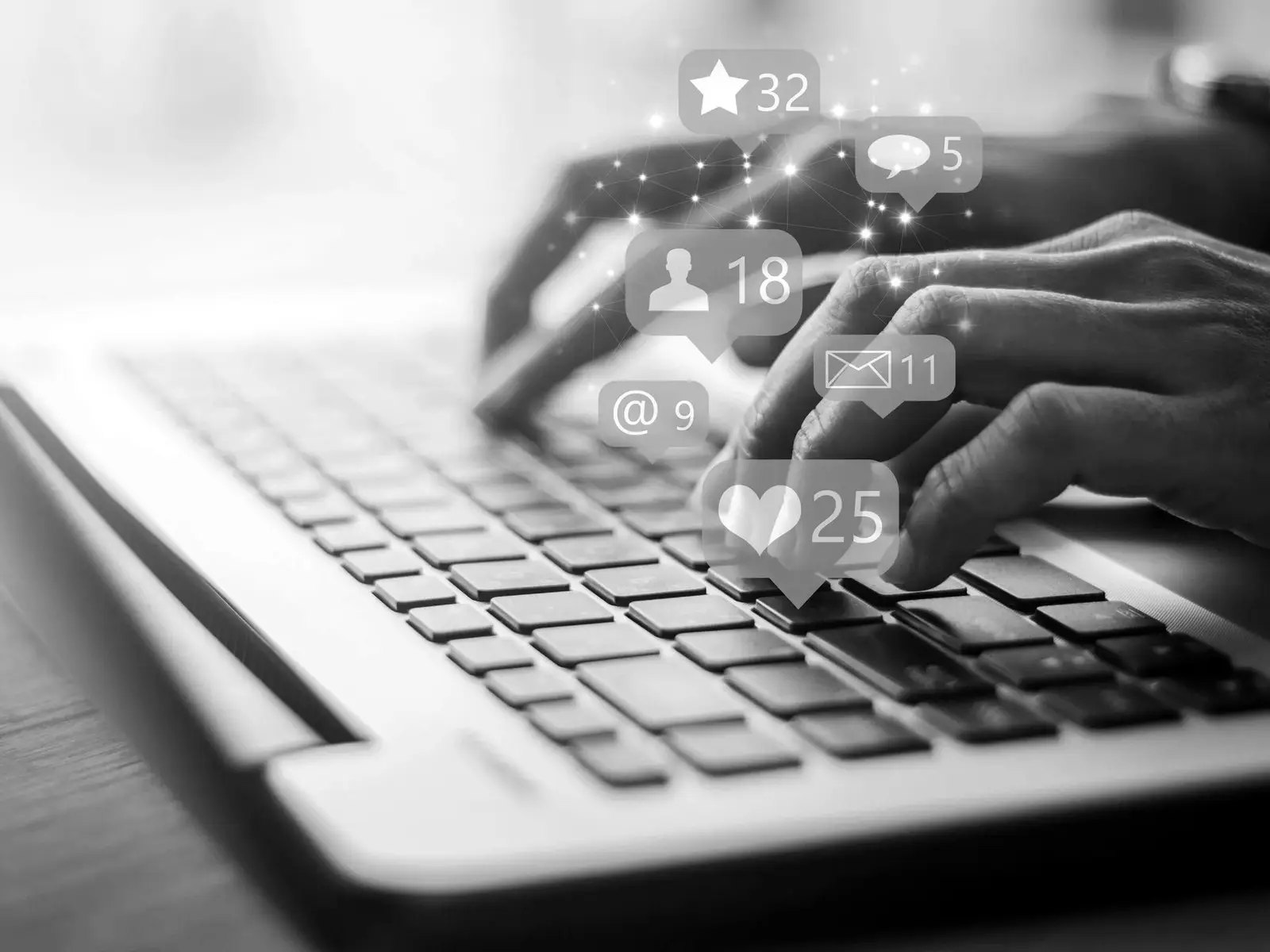 Mãos digitando num notebook, com ícones de curtidas e comentários flutuando sobre o teclado